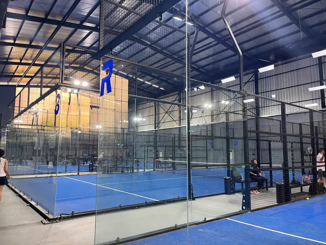Glass padel courts with the R logo banner